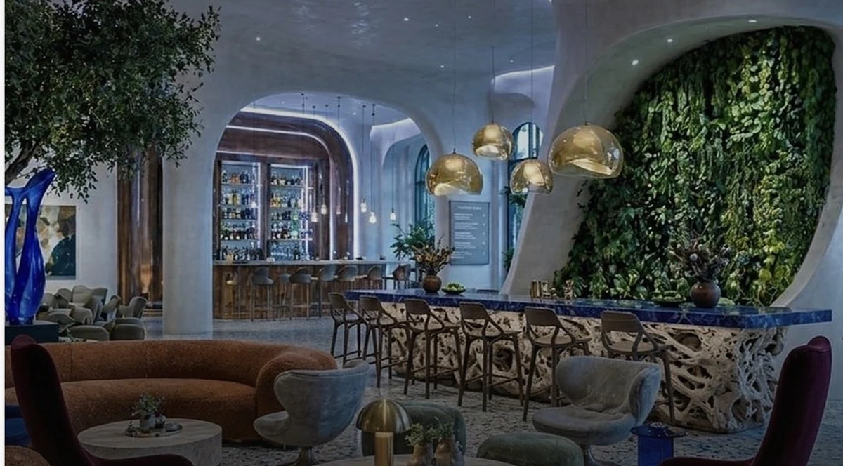 The Orbit lounge: curved plaster walls, bouclé sofas, brass dome pendants and a living plant wall