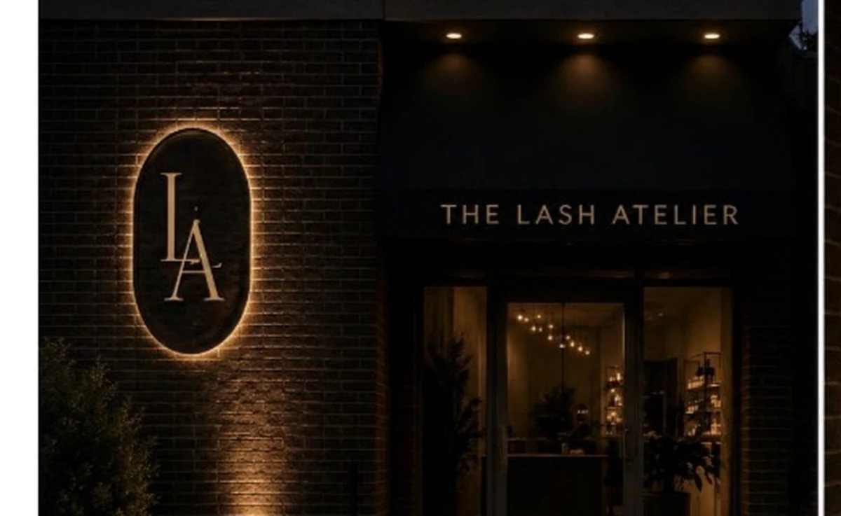 The Atelier at night: black brick, halo-lit oval monogram, warm entry